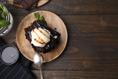 Tasty brownies served with ice cream and caramel sauce on wooden table, flat lay. Space for textの写真素材