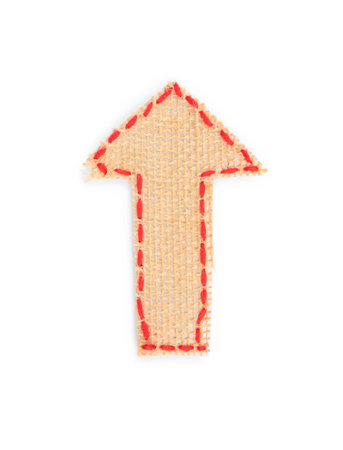 Arrow made of burlap fabric with red stitches isolated on white, top viewの写真素材