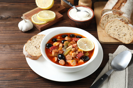 Meat solyanka soup with sausages, olives and vegetables served on wooden tableの写真素材