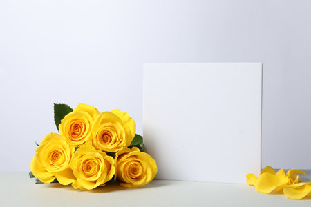 Beautiful presentation for product. Square figure and yellow roses on white table, space for textの写真素材