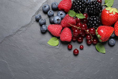Many different fresh ripe berries on dark gray table, flat lay. Space for textの写真素材