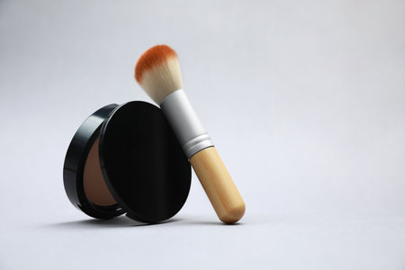 Face powder and brush on light gray background. Space for textの写真素材