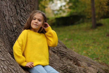Portrait of cute girl near tree in autumn park, space for textの写真素材