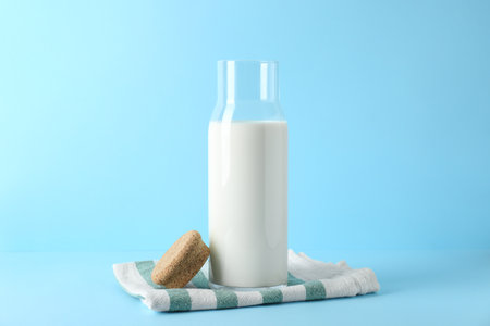 Glass carafe of fresh milk and lid on light blue backgroundの写真素材