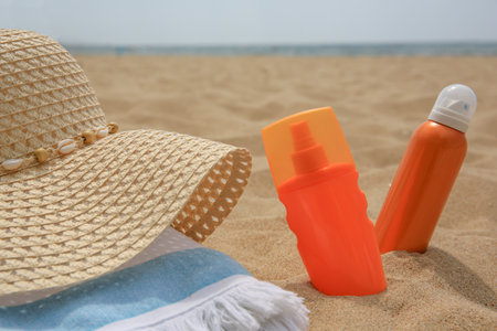 Sunscreens, hat and towel on sand, closeup. Sun protection careの写真素材