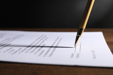 Signing document with pen on wooden table, closeupの写真素材