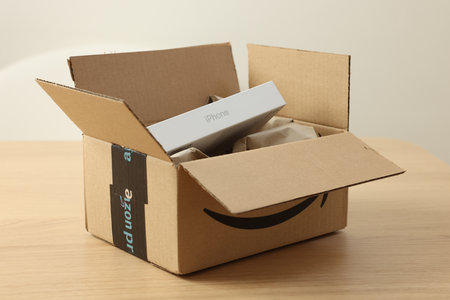 Leiden, Netherlands - October 6, 2023: New iPhone 15 Pro Max and crumpled paper in cardboard box on wooden table. Amazon deliveryのeditorial素材