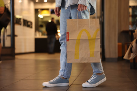 Lviv, Ukraine - September 26, 2023: Woman with McDonald's paper bag in cafe, closeup. Space for textのeditorial素材