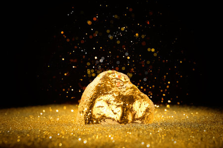 Gold dust falling on gold nugget against black background
