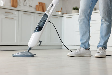 Man cleaning floor with steam mop at home, closeup