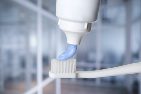 Squeezing toothpaste onto toothbrush against blurred background