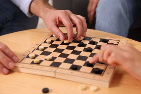 People playing checkers at wooden table, closeup