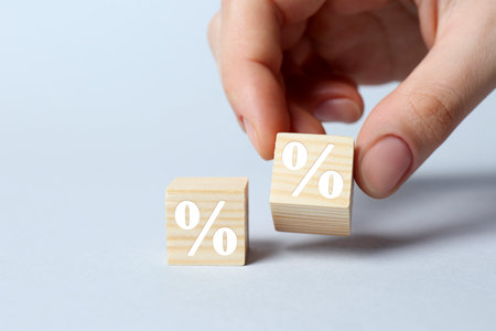 Woman arranging cubes with percent signs on light background, closeup