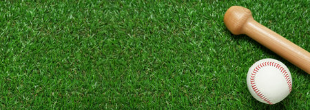 Wooden baseball bat and ball on green grass, top view. Banner design with space for textの写真素材