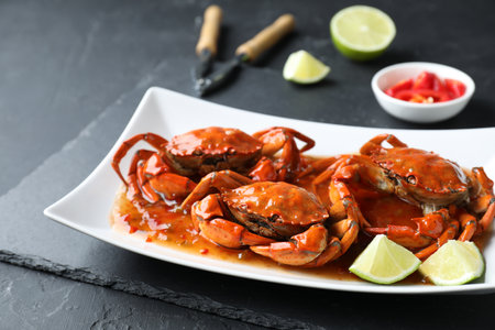 Delicious boiled crabs with sauce and lime on black textured tableの写真素材