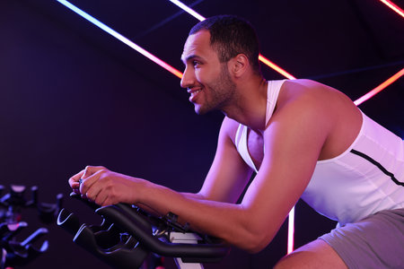 Young man training on exercise bike in fitness club