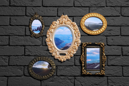 Vintage frames with photos of beautiful landscapes hanging on dark brick wall