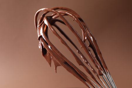 Chocolate cream flowing from whisk on brown background, closeupの写真素材