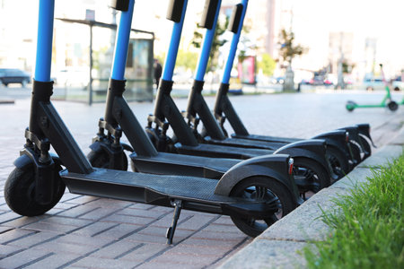 Many modern electric scooters parked on city street. Rental service