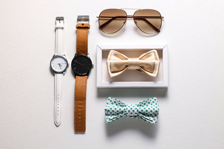 Stylish color bow ties, wristwatches and sunglasses on white background, flat lay