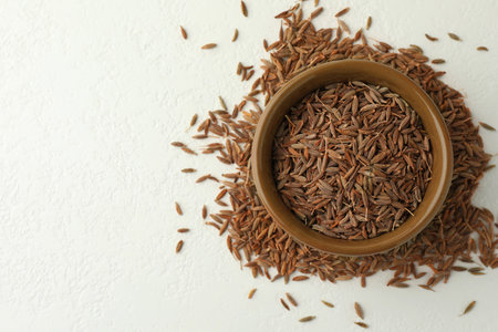 Caraway (Persian cumin) seeds and bowl on white table, top view. Space for textの写真素材