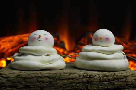 Cute decorative snowmen on wooden surface near fireplace