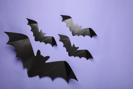Cardboard bats on purple background, flat lay. Halloween celebration