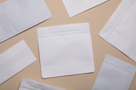 White bags on beige background, flat lay. Space for text
