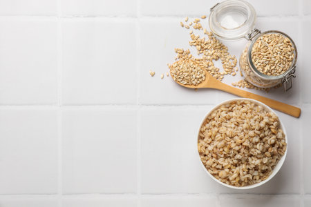 Delicious pearl barley served on white tiled table, flat lay. Space for text