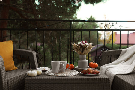 Rest on terrace with rattan furniture. Drink, dessert and autumn decor on tableの写真素材