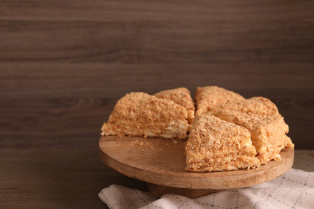 Pieces of delicious Napoleon cake on table, closeup. Space for text