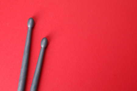 Two gray drum sticks on red background, top view. Space for textの写真素材