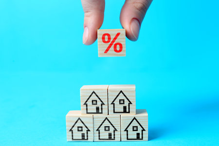 Mortgage rate. Woman building pyramid of cubes with percent sign and house icons on light blue background, closeupの写真素材