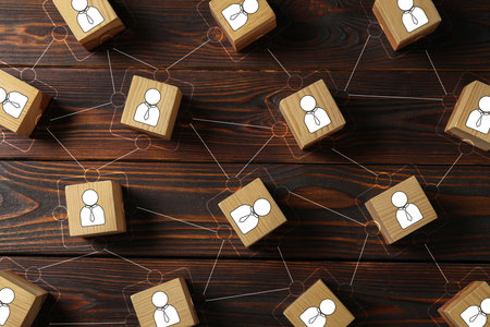 Teamwork. Cubes with human icons linked together symbolizing cooperation on wooden background, top...