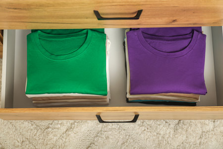 Stacks of different folded shirts in drawer indoors, top view. Organizing clothes