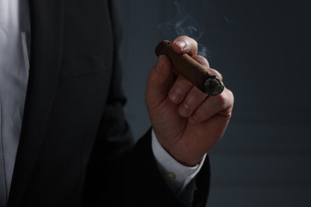 Man smoking cigar on dark gray background, closeup