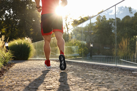 Man running outdoors on sunny day, closeup. Space for text