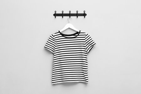 Hanger with striped T-shirt on light gray wall