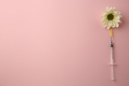 Medical syringe and beautiful chrysanthemum flower on pink background, top view. Space for text