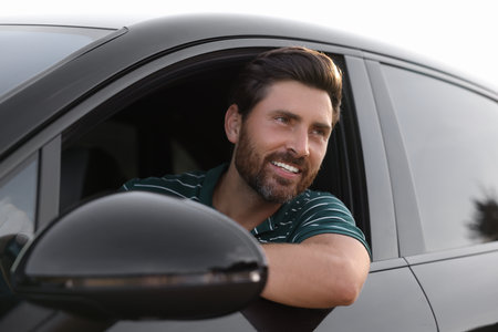 Enjoying trip. Happy bearded man driving his car, view from outsideの写真素材