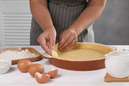 Woman making quiche at white wooden table, closeup