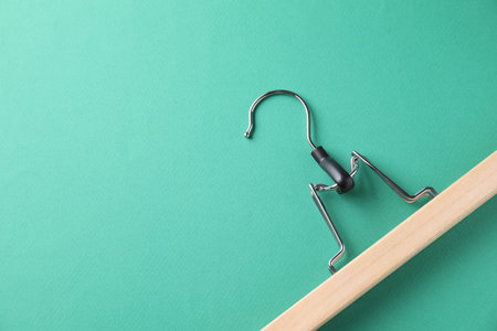 One wooden hanger on dark turquoise background, top view. Space for text