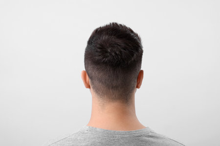 Man with healthy hair on light gray background, back view