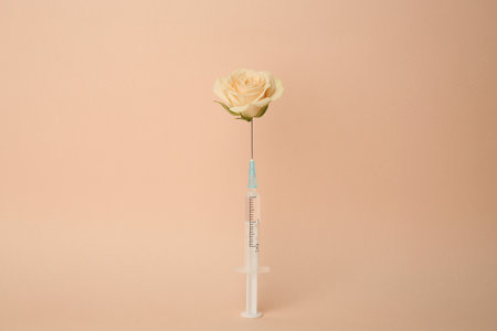 Medical syringe and rose flower on beige backgroundの写真素材