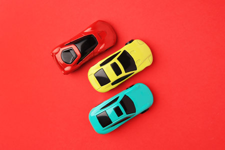 Different bright cars on red background, flat lay
