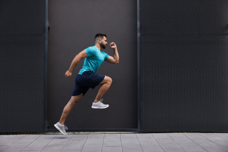 Young man running near building outdoors. Space for text