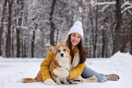 Woman with adorable Pembroke Welsh Corgi dog in snowy parkの写真素材
