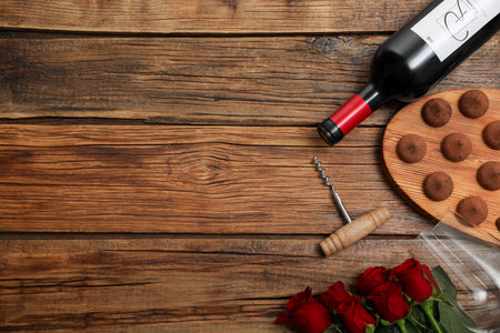 Red wine, chocolate truffles, corkscrew and roses on wooden table, flat lay. Space for textの写真素材