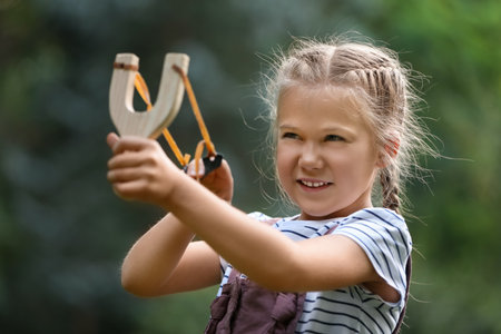 Little girl playing with slingshot in park