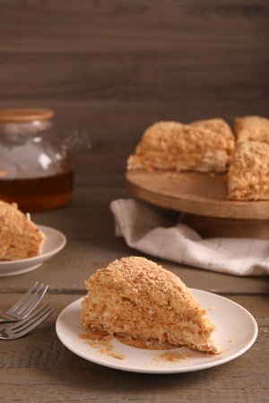 Piece of delicious Napoleon cake served on wooden table, closeup